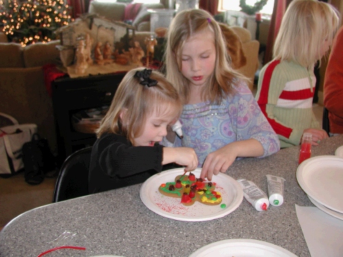 Brianna Hulme helping Karen Crapo -- just how much candy can you fit on one gingerbread man?