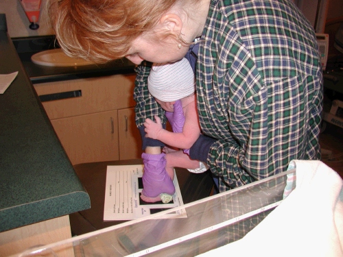 The nice nurse with the purple gloves is helping Jackson with his footprints.  Look at what they put you through within minutes of being born -- good grief!