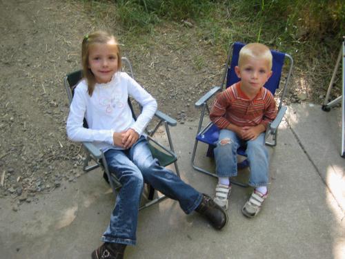 Karen and Jackson Crapo sitting on their little chairs that fold up to be backpacks they can carry themselves.