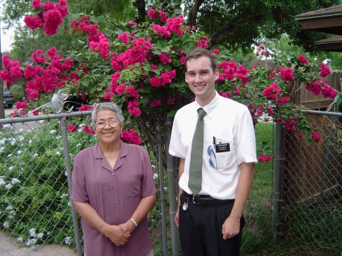 Elder Brown with Sister Trevio in front of beautiful Bougainvillea flowers.