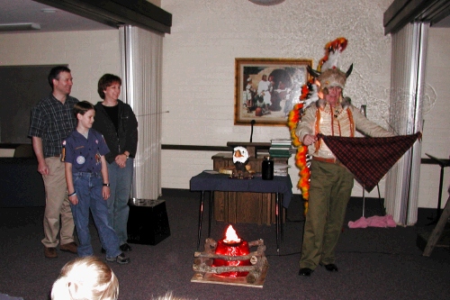 It's hard to tell, but Elliot's neckerchief has flames around the edges.  The fact that it survived the flames means that Elliot was telling the truth - or so the legend goes...