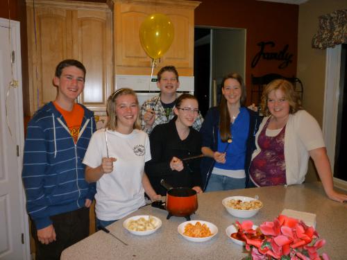 The friends enjoying the dipping into the chocolate fondue for dessert.